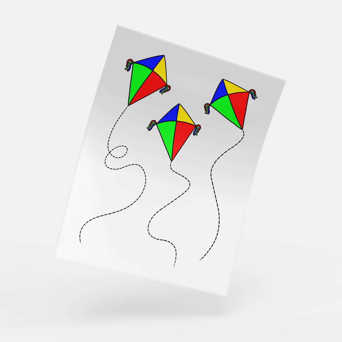 A digital mockup of an activity sheet featuring three colorful kites flying in the sky, drawn with black lines on a slightly curved white paper. Each kite is a classic diamond shape with a rainbow of red, yellow, blue, and green panels, and long, flowing tails following wavy lines.